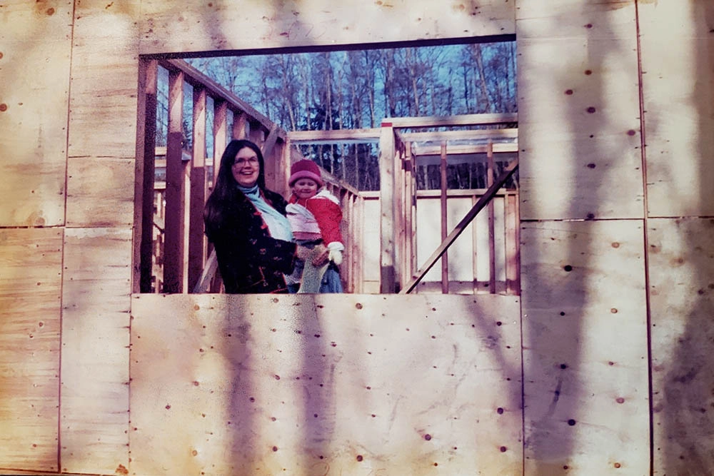 Mother and young child looking through a framed window opening during early construction