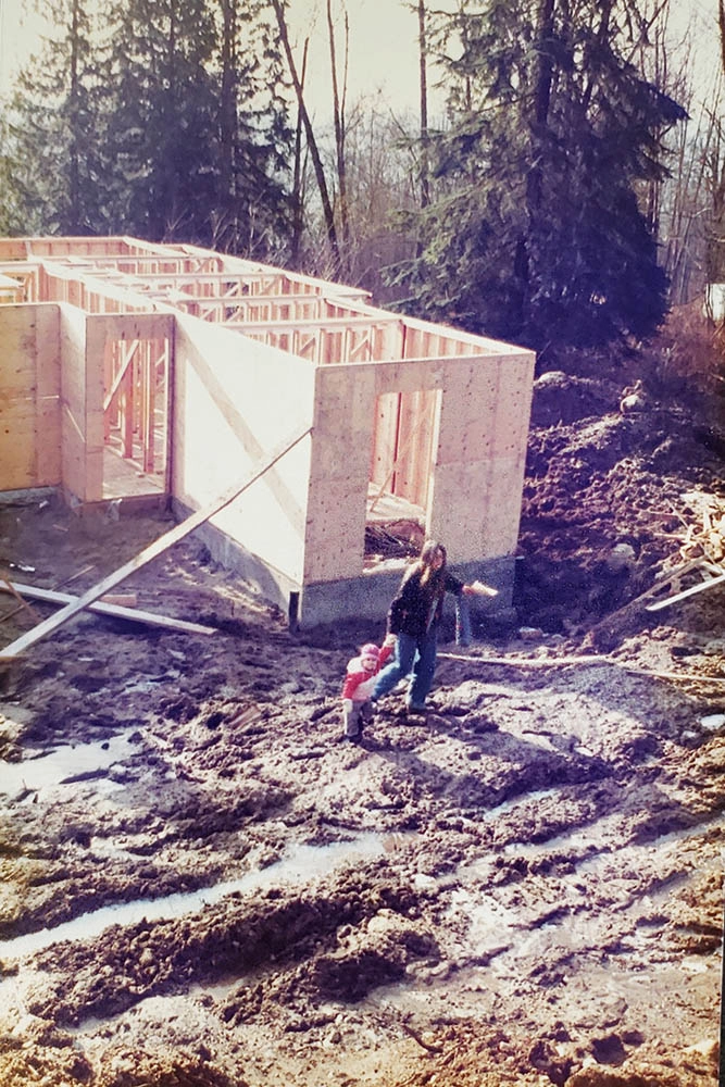 Mother navigating mud fields next to concrete foundation framing blocks