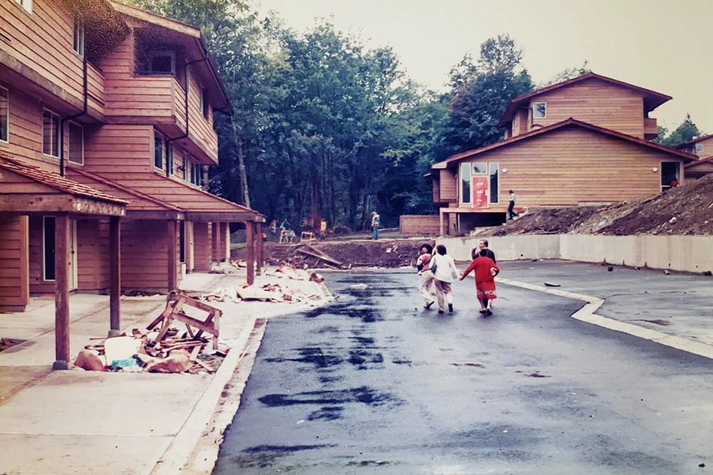 Co-op members walking down the newly paved asphalt access road among completed townhomes
